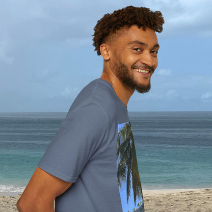 Side view of a man by the ocean wearing a slate blue Coconut Tree T-shirt, with part of the coconut palm photograph visible on the front.