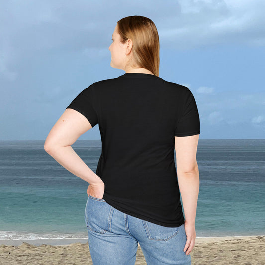 Back view of a woman wearing a black Caribbean Coastal Sea Rocks T-shirt featuring a photograph of a rocky shoreline and ocean waves.
