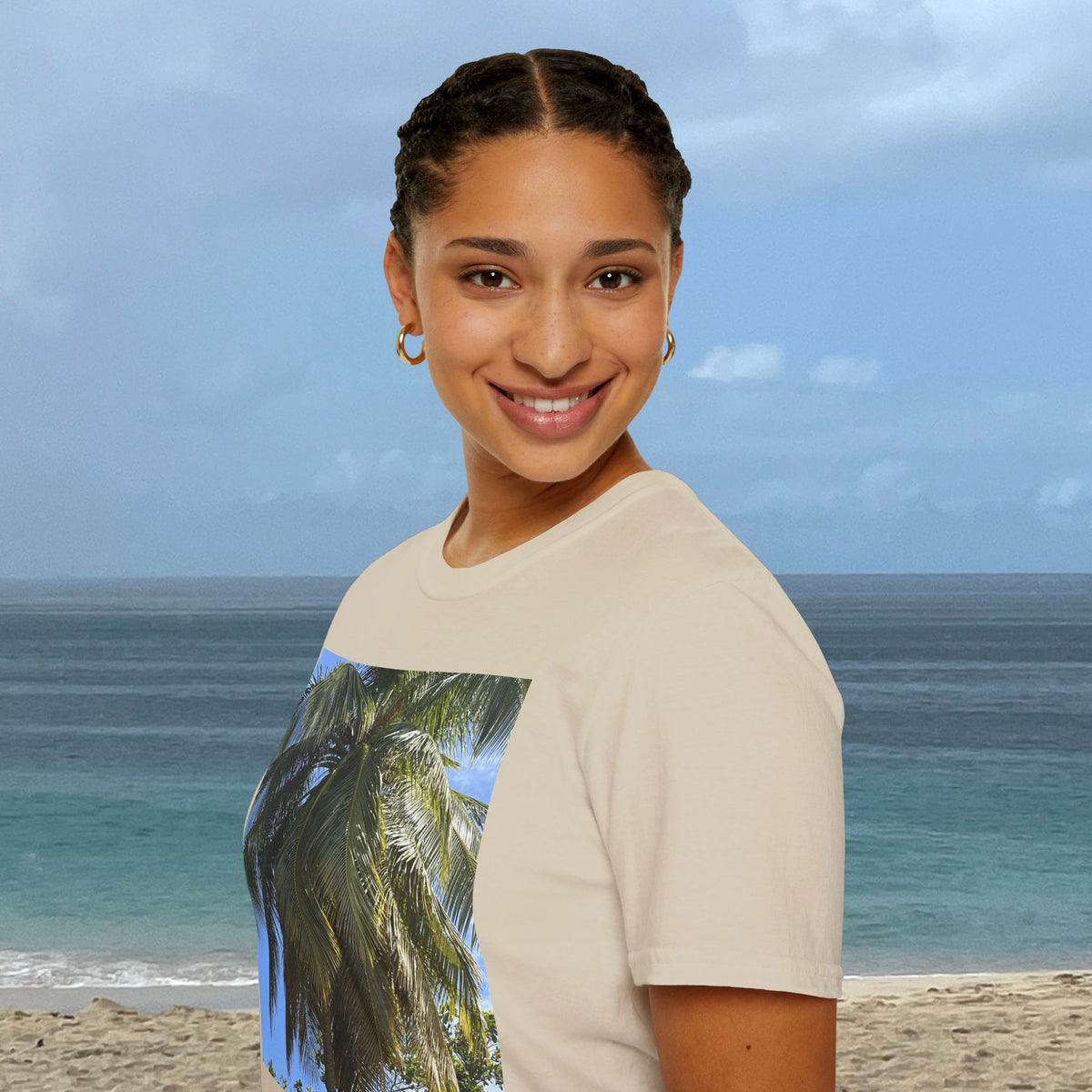 Woman wearing a natural-colored Coconut Tree T-shirt with a coconut palm photograph on the front, standing by the ocean.